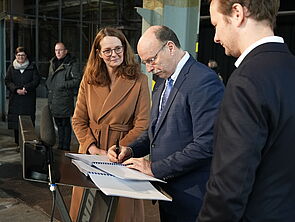 Museumschef Michael Gericke unterzeichnet ein Papier. Neben ihm steht Kulturministerin Bettina Martin.