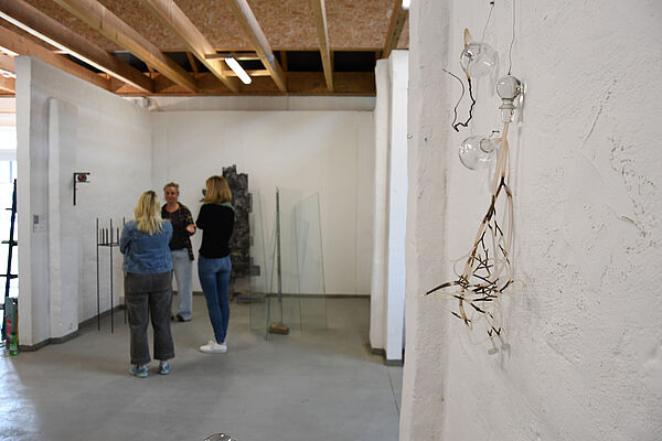 Frauen stehen zwischen Kunstwerken.