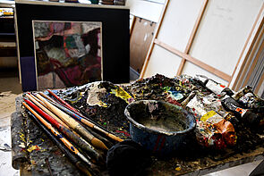 Malutensilien. Farben. Pinsel. Im Hintergrund Bilder.