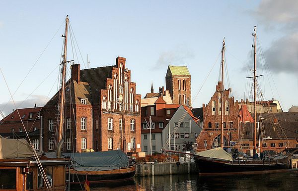 Im Hafen von Wismar liegen zwei Segelboote. Dahinter stehen Häuser der Altstadt. 