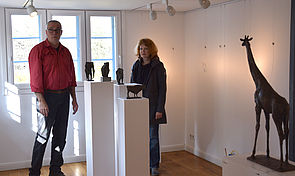 Ein Mann und eine Frau stehen in einem Raum neben Tier-Skulpturen. 