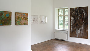 Kunstwerke hängen in einem hellen Raum.