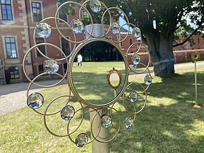 Im Garten steht ein Spiegel mit Glitzersteinen.