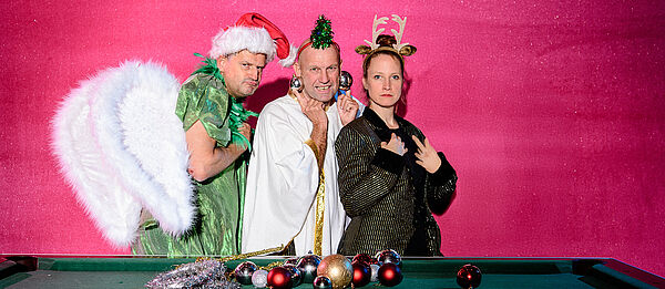 Das Foto zeigt 2 Männer und eine Frau in Weihnachts-Dekoration gekleidet.