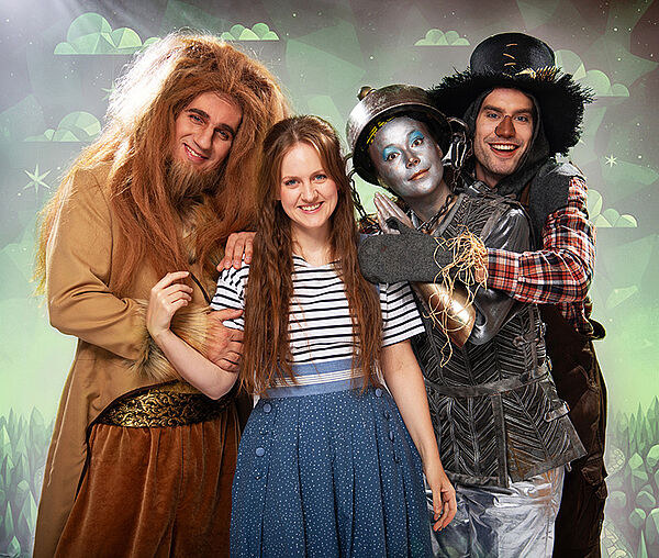 Vier Schauspieler in Kostümen stehen nebeneinander.