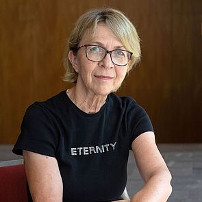 Eine Frau sitzt auf einem Stuhl. Die Frau ist Eva Martina Weyer.