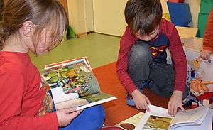 Zwei Kinder schauen sich Bücher an.