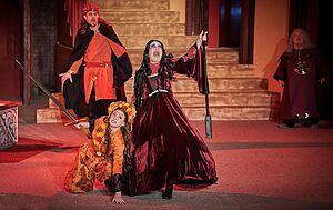 Zwei Frauen auf einer Bühne. Eine steht und singt. Eine hockt zu ihren Füßen.