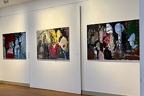 Drei Bilder hängen an der Wand.