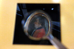 Unter einer Lupe ist das Bild eines Mannes zu erkennen.