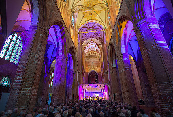 Der bunt erleuchtete Dom von innen mit vollem Publikum. Im Hintergrund die Bühne.