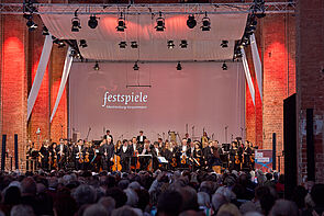 Blick über das Publikum auf die Bühne zum Orchester.