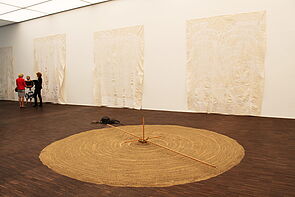 Auf dem Boden liegt ein Kreis aus Fäden und Sand.