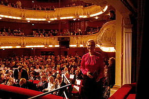 Eine Frau im Theater. Sie geht aus dem Saal an der Seite auf die Bühne.