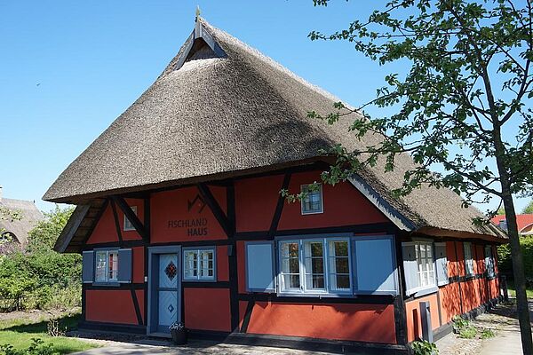 Ein rotes, restgedecktes Haus mit weißen Fenstern.