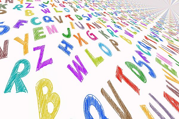 Auf einem weißen Blatt verteilen sich von A bis Z viele bunte Großbuchstaben. 