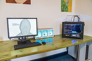 Auf einem Schreibtisch stehen ein Monitor, eine Tastatur sowie Geräte zum Experimentieren.