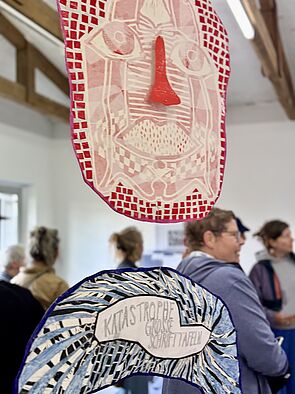 Im Hintergrund sind Gäste. Vorn Ausstellungsstücke.