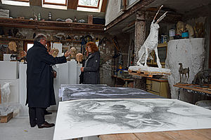 Frauen und Männer stehen im Atelier von Michael Mohns und schauen sich seine Kunst an.
