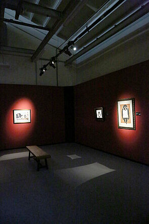 Blick in einen dunklen Raum. Die Bilder sind angestrahlt.