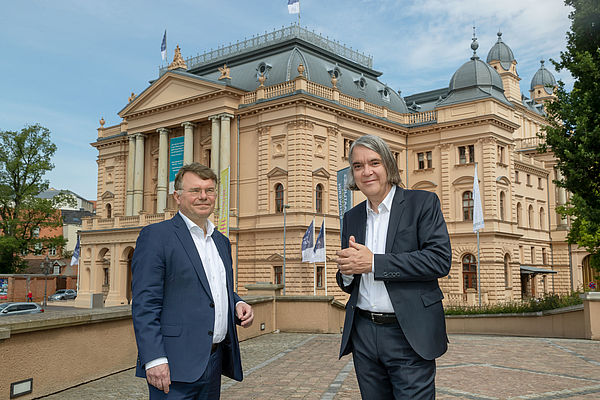 Christian Schwandt und Hans-Georg Wegner stehen vor dem Mecklenburgischen Staatstheater. 