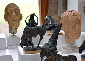 Fünf Skulpturen, die Köpfe und Tiere zeigen. 