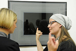 Birgit Hesse und Ramona Seyfarth stehen vor einem Bild und sprechen miteinander.