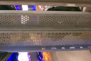 Zwei Personen sitzen auf einem Gerüst und arbeiten.