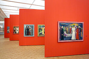 Vier rote Wände. Auf jeder Wand hängt ein Bild.