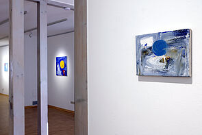 Blick in den Ausstellungsraum. Im Hintergrund hängen beleuchtete Bilder.