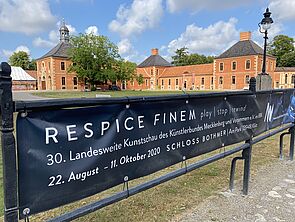 Auf dem Weg zum Schloss hängt ein Banner mit dem Motto der Ausstellung. 