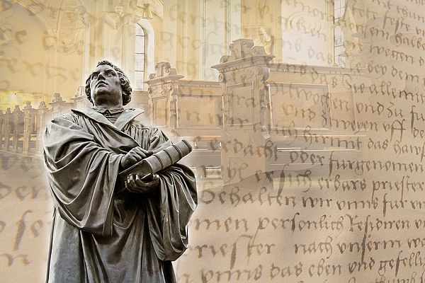 Ein Denkmal von Martin Luther in Worms. Den Hintergrund füllen eine blasse Collage aus Zeilen aus der Bibel und Kirchenbänken. 