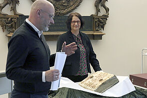 Ein Mann und eine Frau stehen an der Chronik und sprechen zu den Gästen.