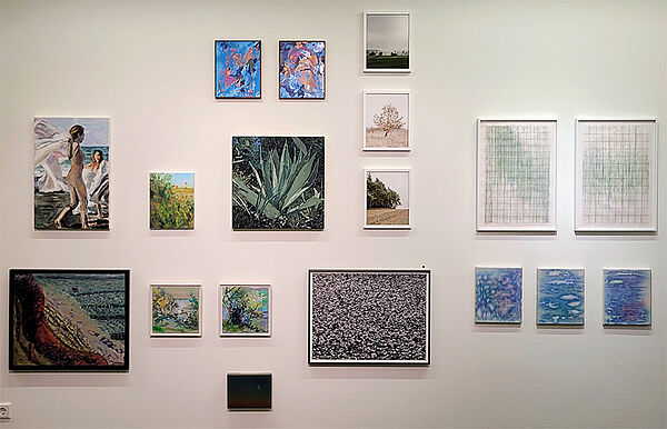 Eine Wand. An der Wand hängen große und kleine Bilder.