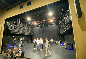 Vor und auf der Bühne stehen 14 Menschen: Journalisten, Kameramänner, Theatermitarbeiter. 