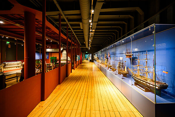 Ein langer Gang. Links und rechts stehen Ausstellungsschiffe in Vitrienen
