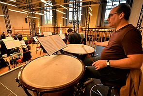 Andreas Winkler, ein Mann Anfang 50, sitzt mit Schlegeln in der Hand vor zwei Pauken.