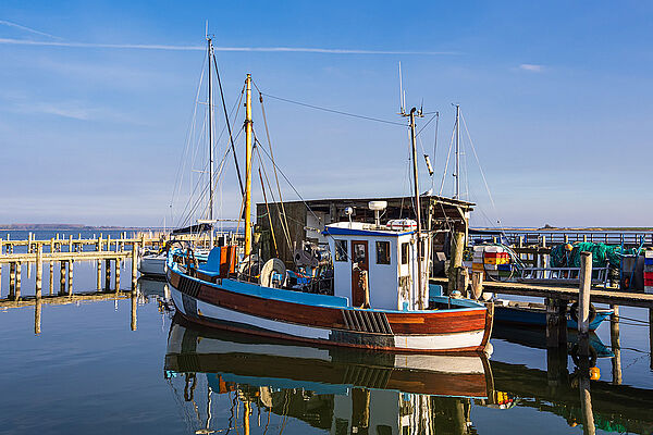Ein kleines Fischerboot. Es liegt an einem Steg.