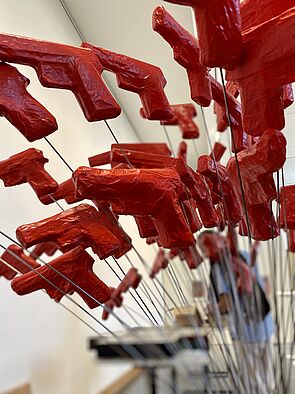 Kleine rote Pistolen stecken auf Drahtstäbe gespießt in einem Gefäß. 