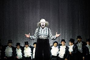 Ein geschminkter Schauspieler singt auf der Bühne.