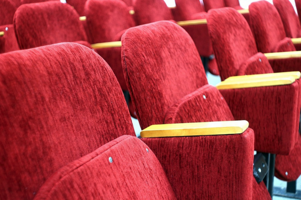 Rote Sessel stehen in einem Kino.