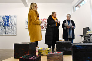 Drei Frauen in einem Atelier begutachten Kunstarbeiten.