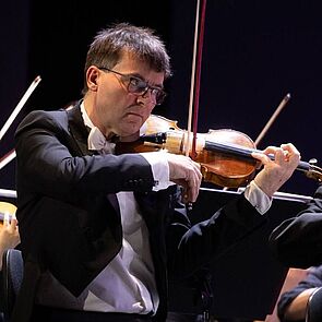 Volker Reinhold spielt eine Geige bei einem Konzert mit dem Orchester.