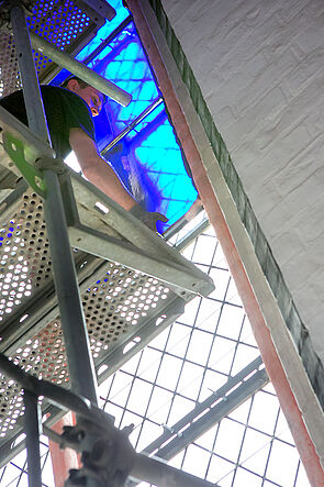 Ein Mann arbeitet auf einem Gerüst am Kirchenfenster.