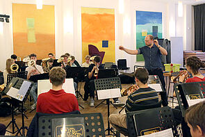 Blick auf die komplette Band. Der Leiter dirigiert.