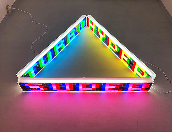 Eine Skulptur in grellen Fragen. Die Aufschrift: Turbo. Hyper. Super.