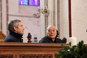 Zwei Männer sitzen auf einer Kirchenbank im Dom.