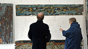 Mitglieder der Kunstkommission stehen vor Gemälden. 