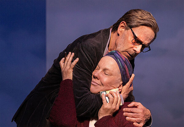 Eine Frau und ein Mann. Beide halten sich im Arm. 