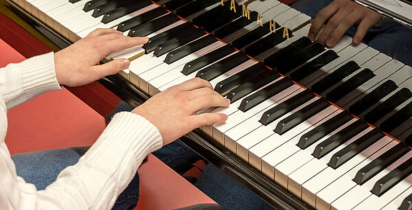 Zwei Hände spielen Klavier.